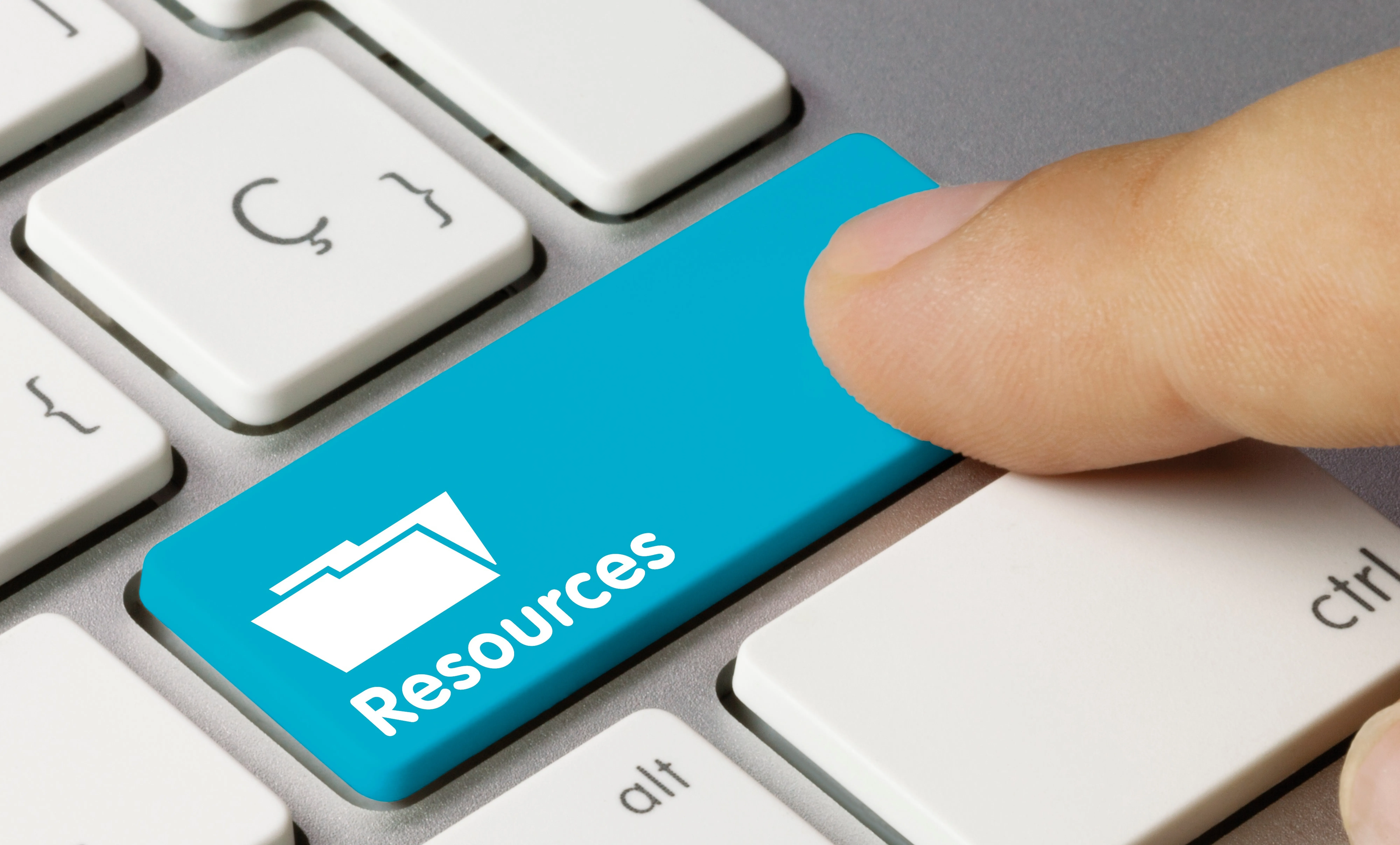 A finger pressing a 'resources' button on a keyboard