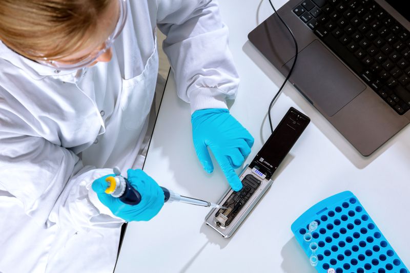 MinION Mk1D attached to a laptop on a lab workbench - open, pipetting above - Option 3