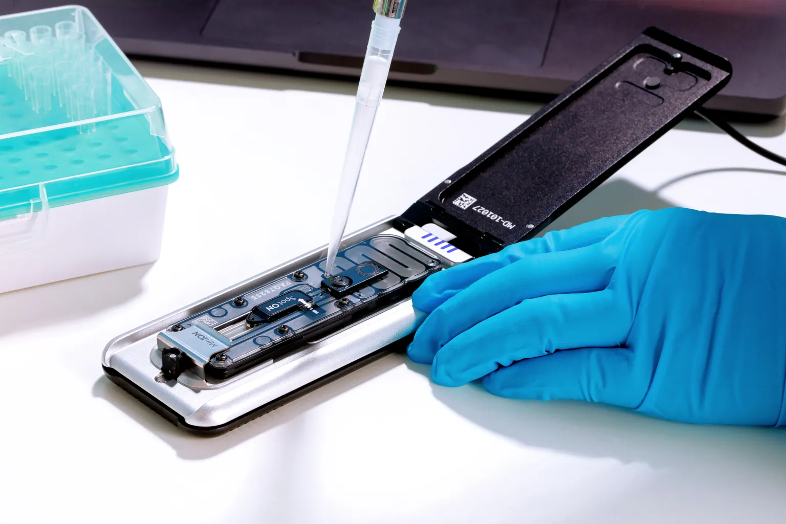 Mk1D attached to a laptop on a lab workbench - open, pipetting copy